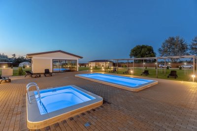 Два ночных бассейна с синей подсветкой и шезлонгами на брусчатке